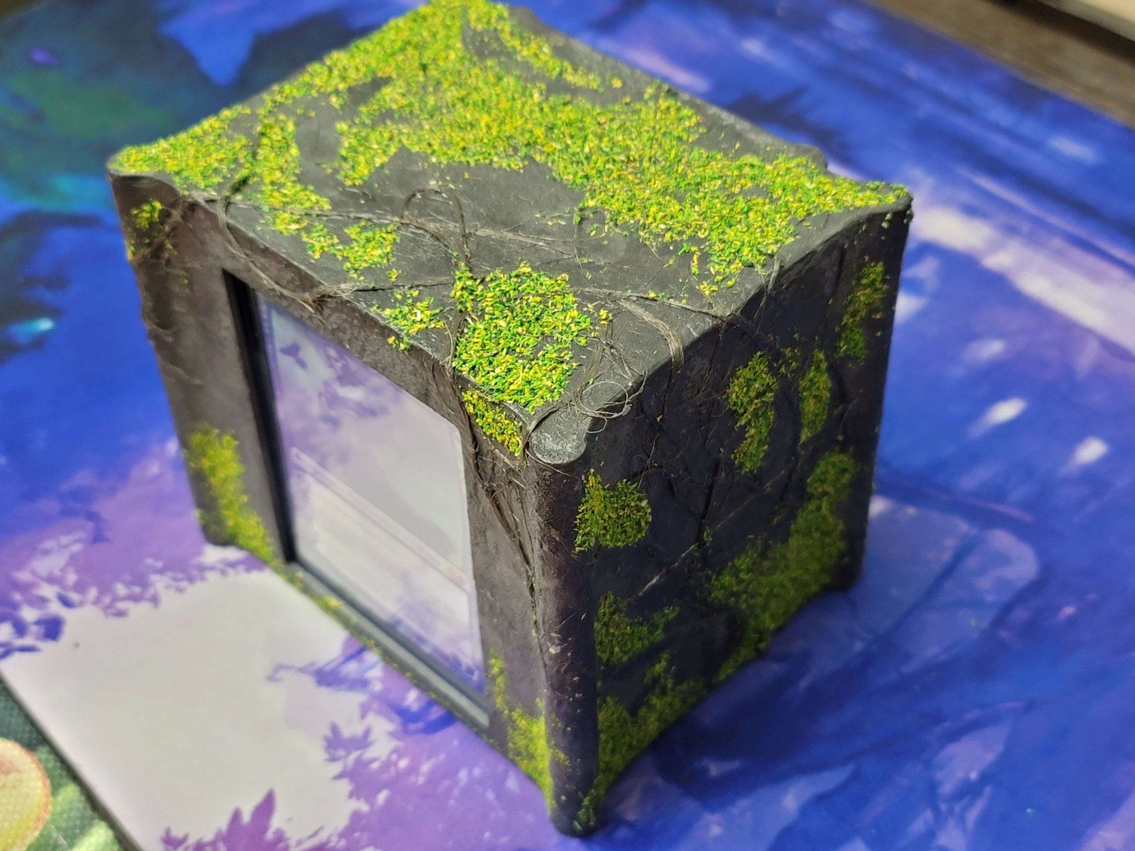 The stone deck box from above, its top covered in moss