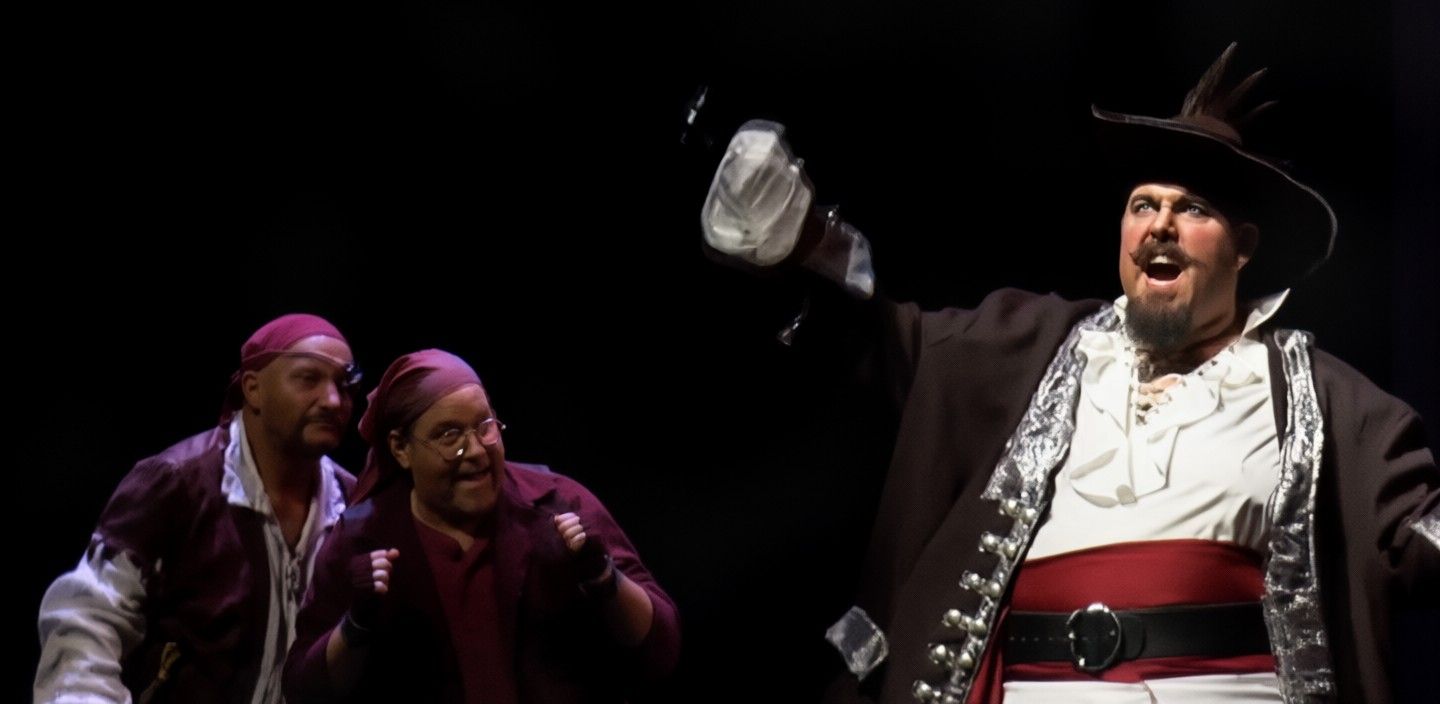 Darrell Calk as Captain Hook, mid-monologue, with two of his pirates